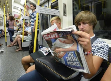 A tube passenger reads a copy of The Sun newspaper featuring a picture of the newborn baby of Catherine, Duchess of Cambridge and Britain's Prince William, on the London underground